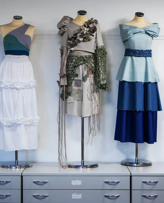 A collection of creative fashion outfits displayed on mannequins, showcasing student work. A collection of creative fashion outfits displayed on mannequins, showcasing student work.